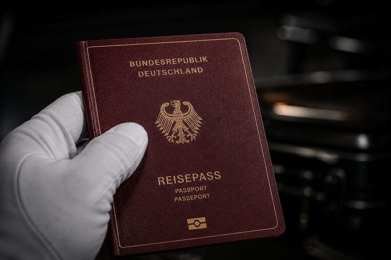 Behandschuhte Hand hält einen deutschen Reisepass